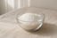 Ultra realistic product photo of Paraffin wax granules in a glass bowl on beige linen fabric, soft natural daylight, minimal style, Instagram aesthetic